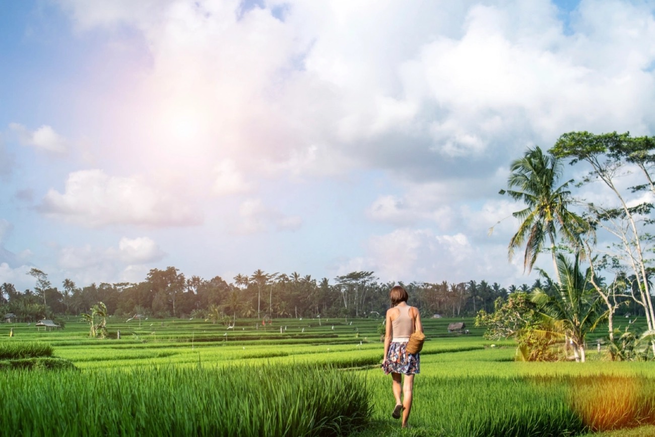 A young person walking through an open field at golden hour