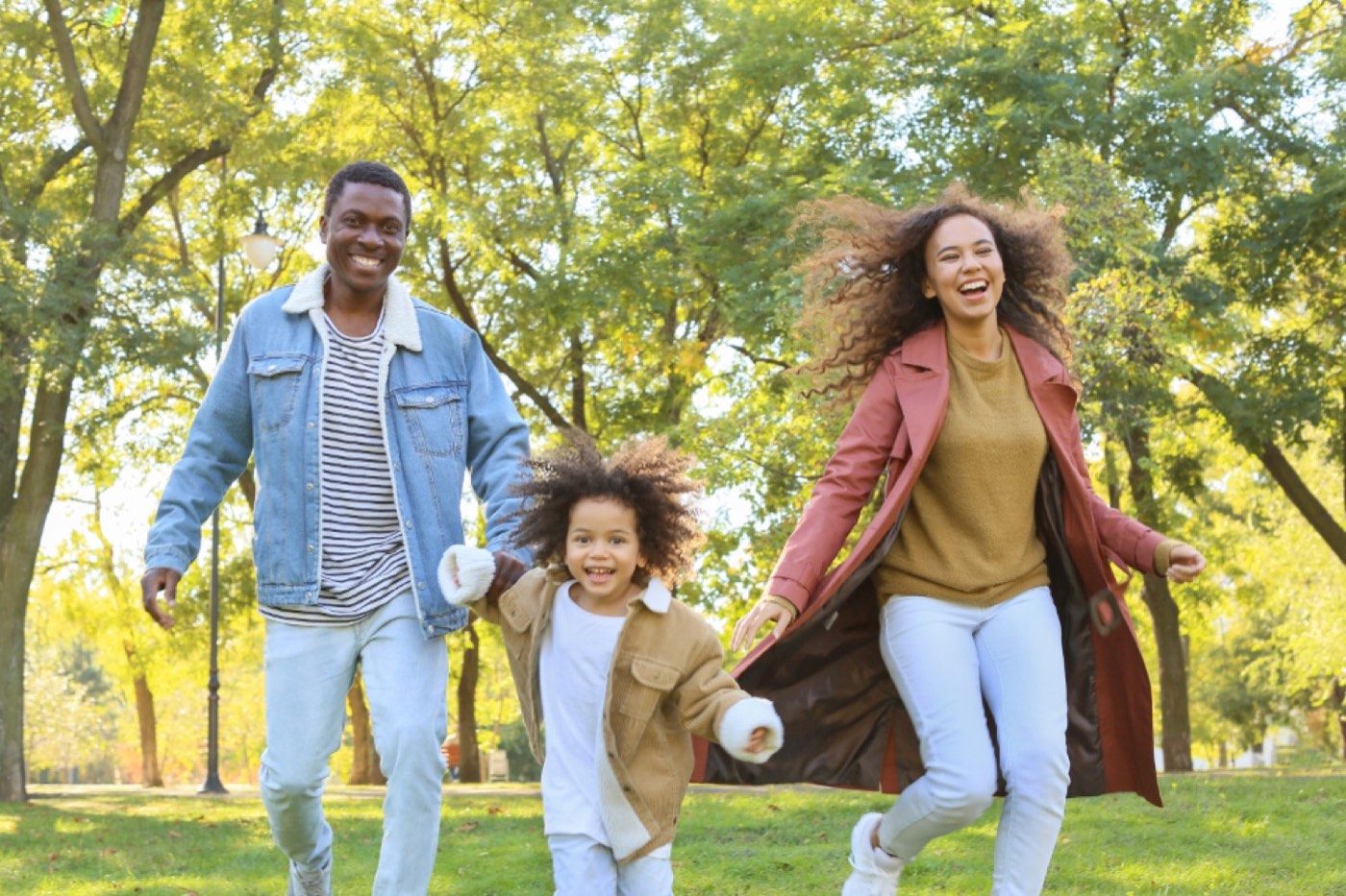 A family walking hand in hand through a sunny park